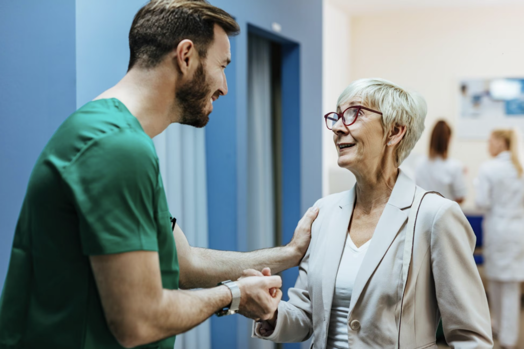 A volunteer in the hospital holding the hand of an elderly woman