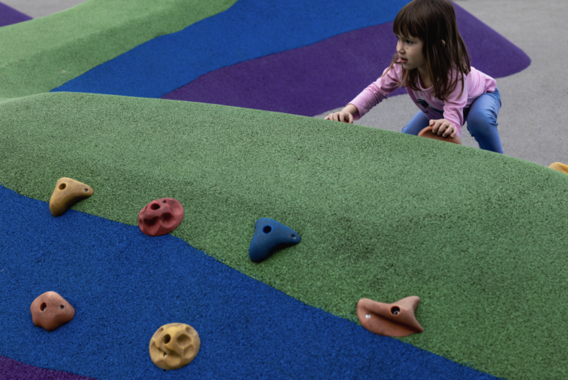 The girl is engaged in rock climbing in the children's amusement park