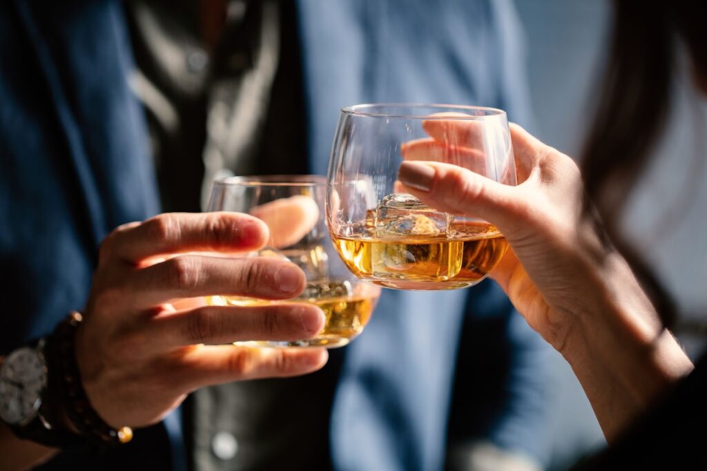 Two people holding glasses with alcohol